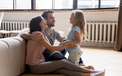 Junge Eltern spielen mit ihrer kleinen Tochter in ihrer sanierten Wohnung