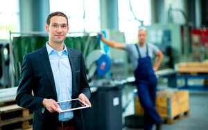 Person mit Tablet in der Hand steht in einer Fabrik