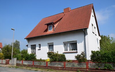 Alleinstehendes Jaus mit Vorgarten an einer Strraße vor blauem Himmel