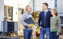 3 lächende Menschen vor einem Haus